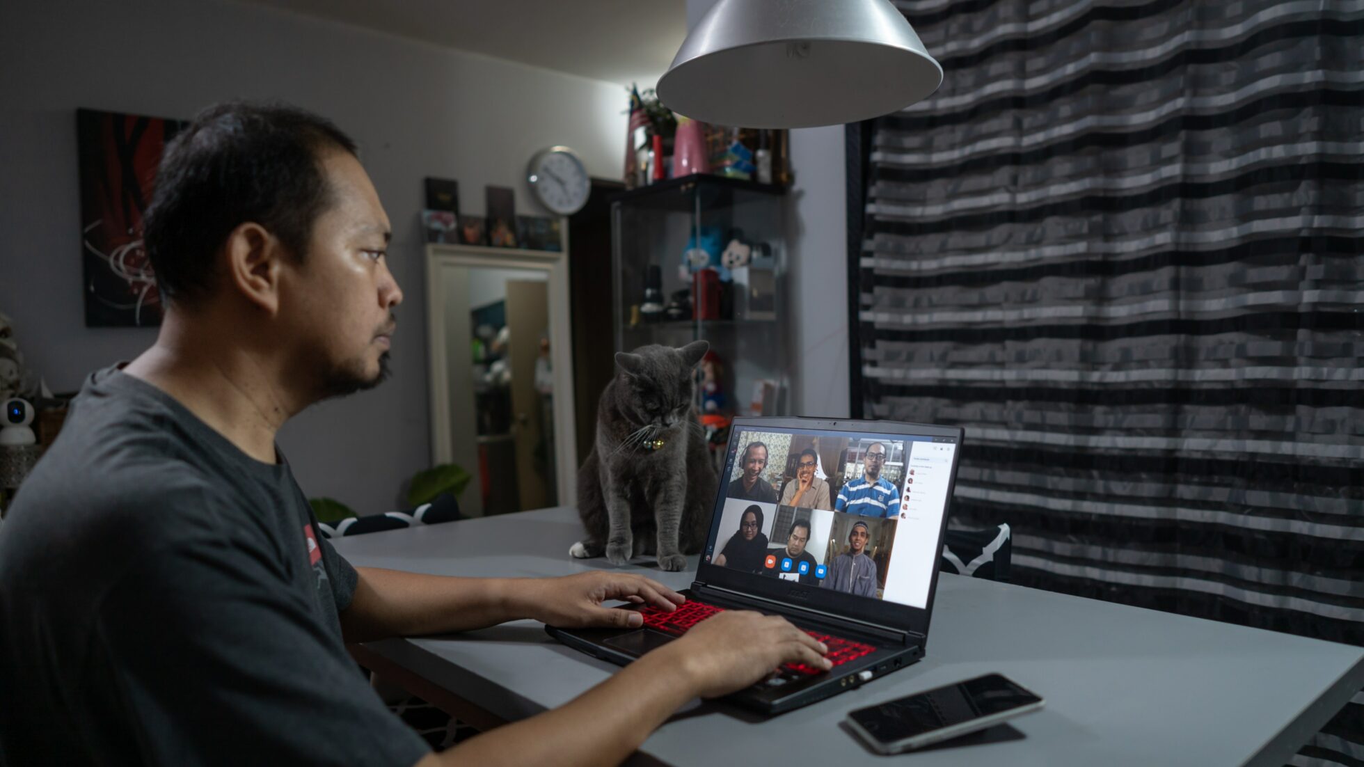 a man is on a zoom call with his cat watching from the size