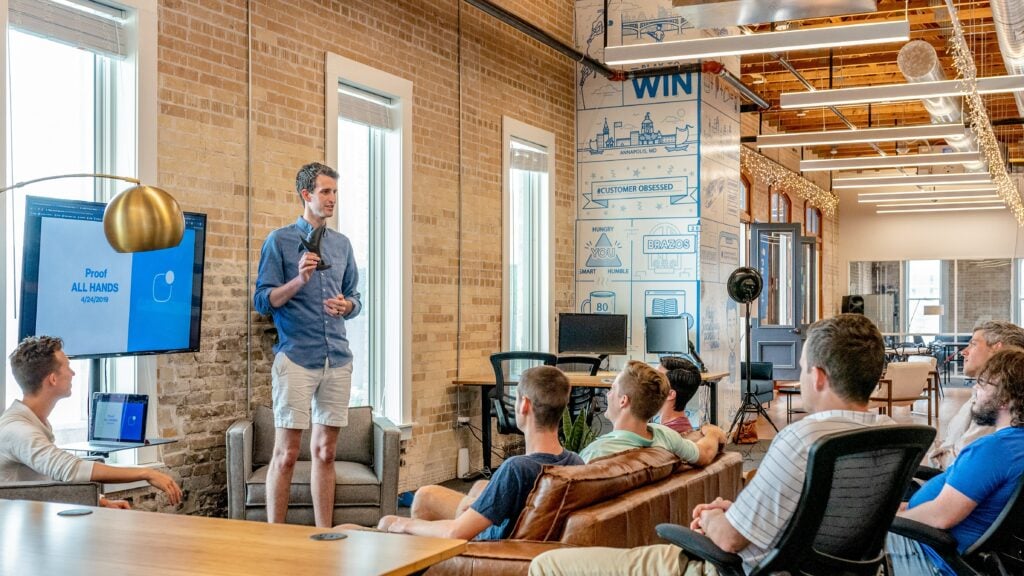 Man presents at business meeting in front of crowd in quirky office