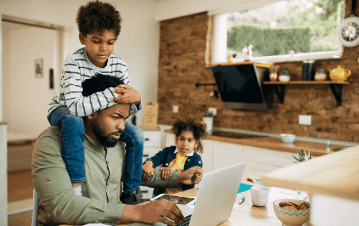 Kid sits on father's shoulder while he works at laptop