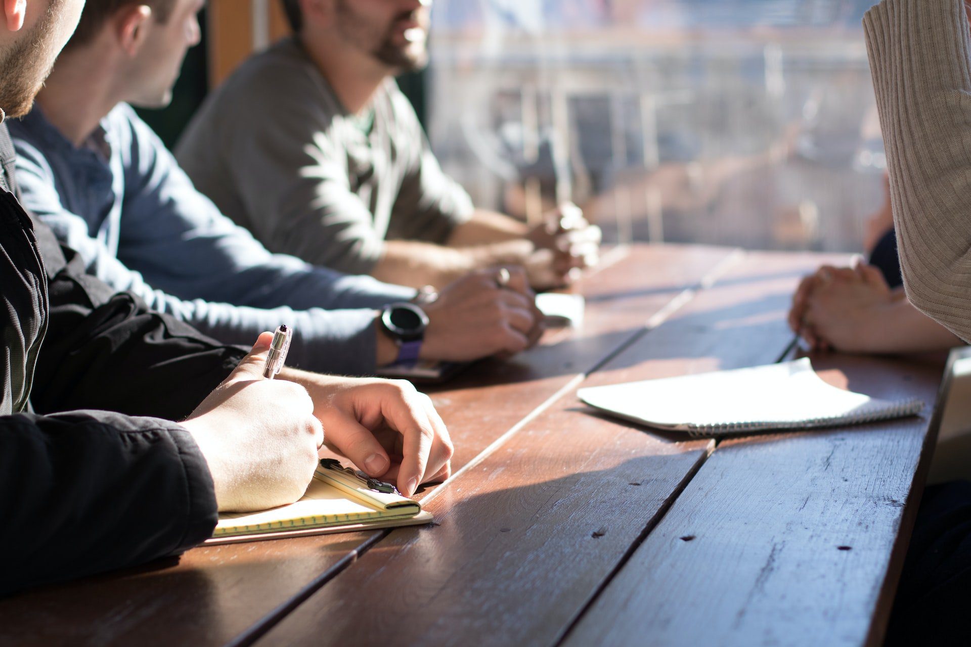 People sit around wooden table and have meeting