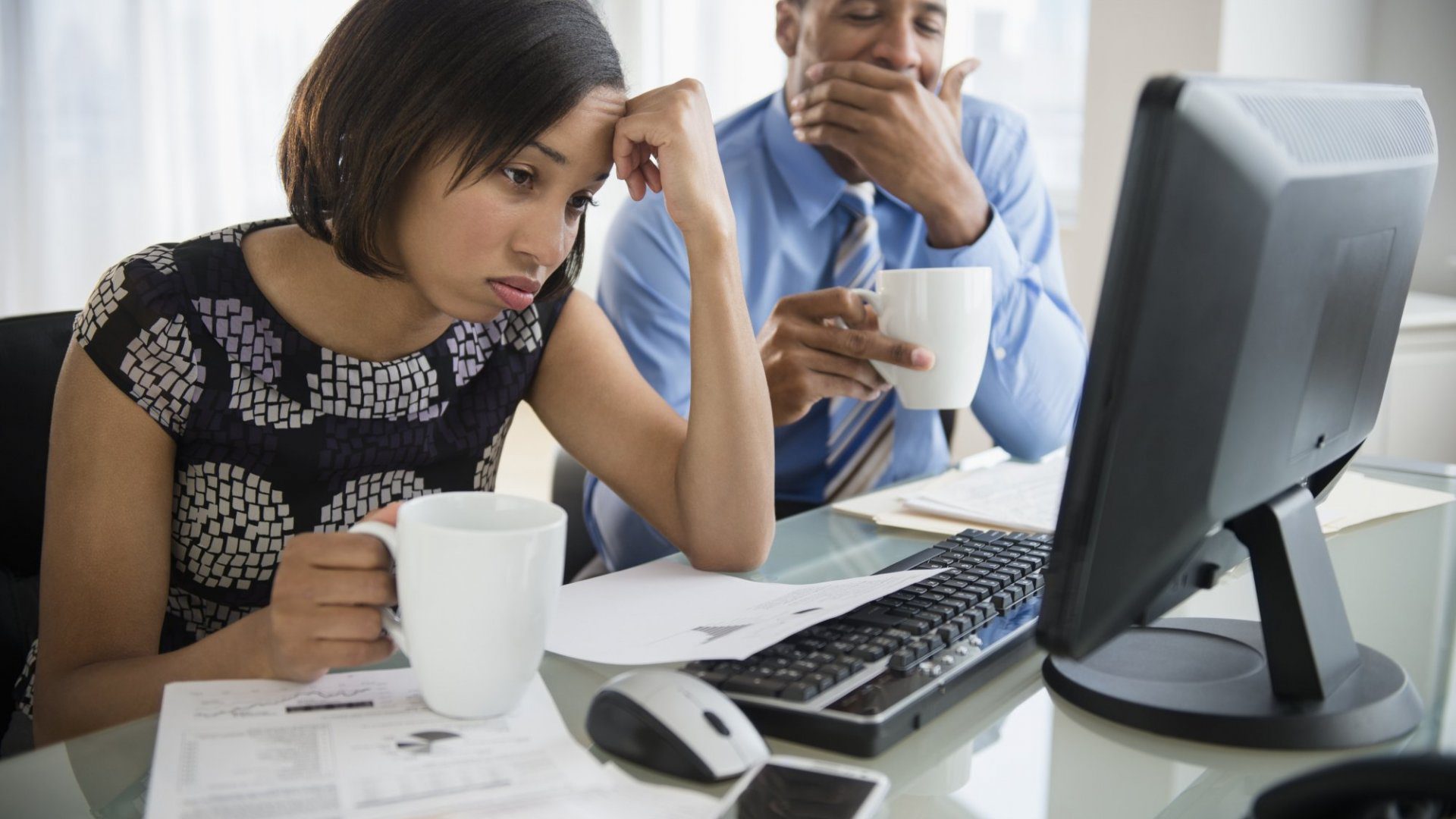 Two office workers are bored and yawning during meeting