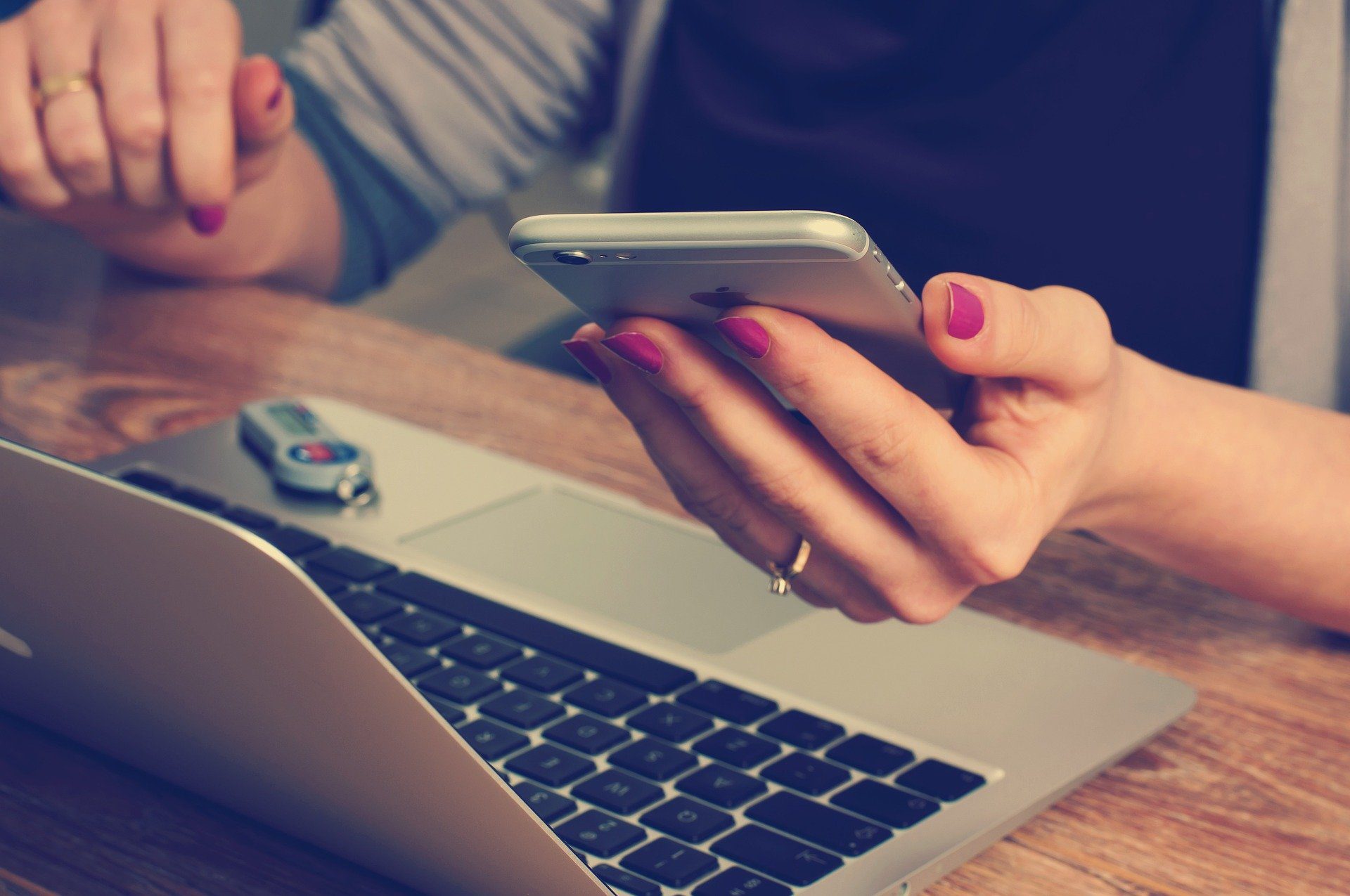 Person, die durch ihr Mobiltelefon vom Laptop abgelenkt wird