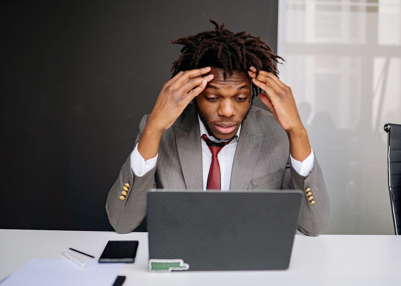 Un homme en costume est frustré par ce qu'il voit sur son ordinateur portable.