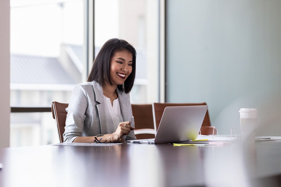 Woman smiles in front of laptop in office