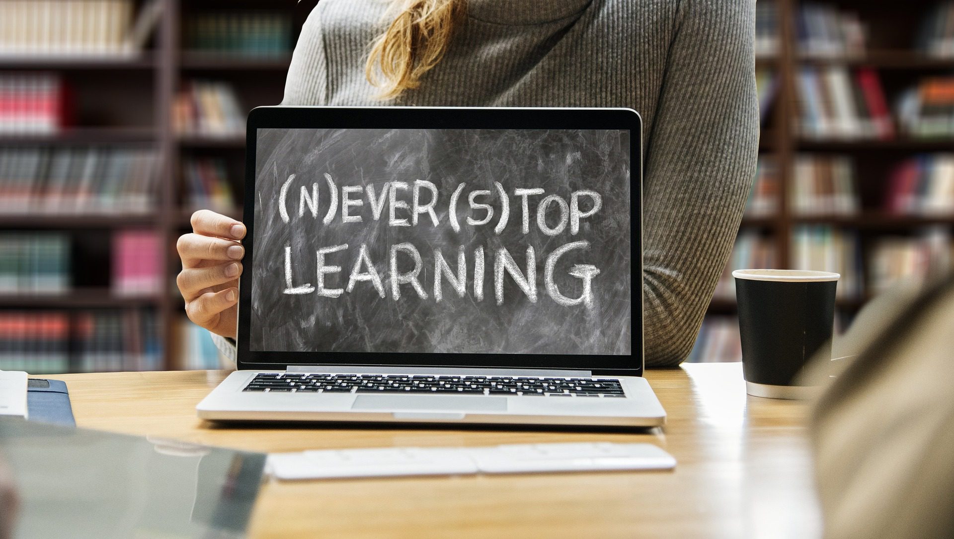 黒板に「Never Stop Learning」と書かれ、括弧内にNとSが書かれているようなノートパソコン