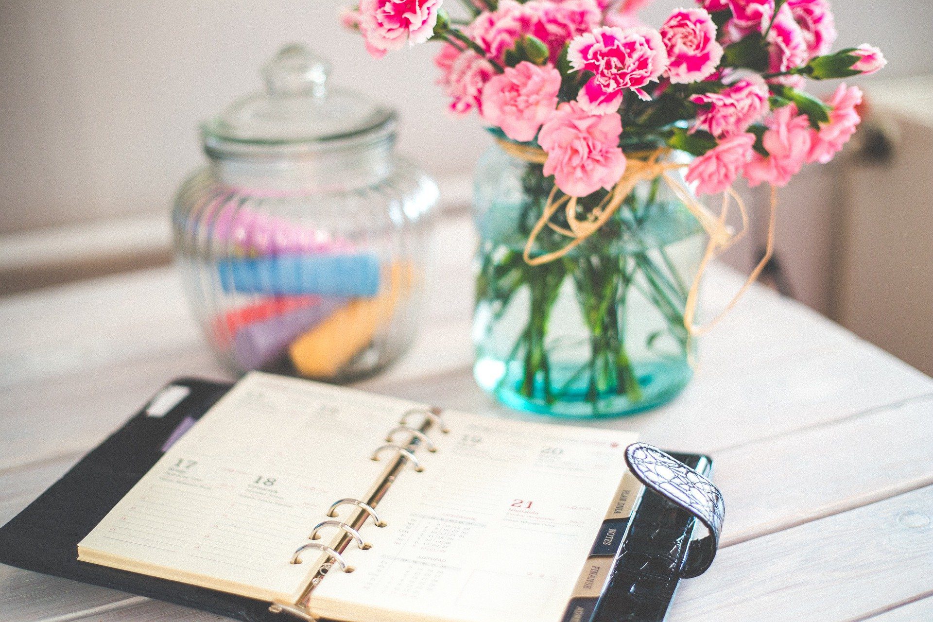 oragnizer on a desk with some brightly coloured flowers and a glass jar