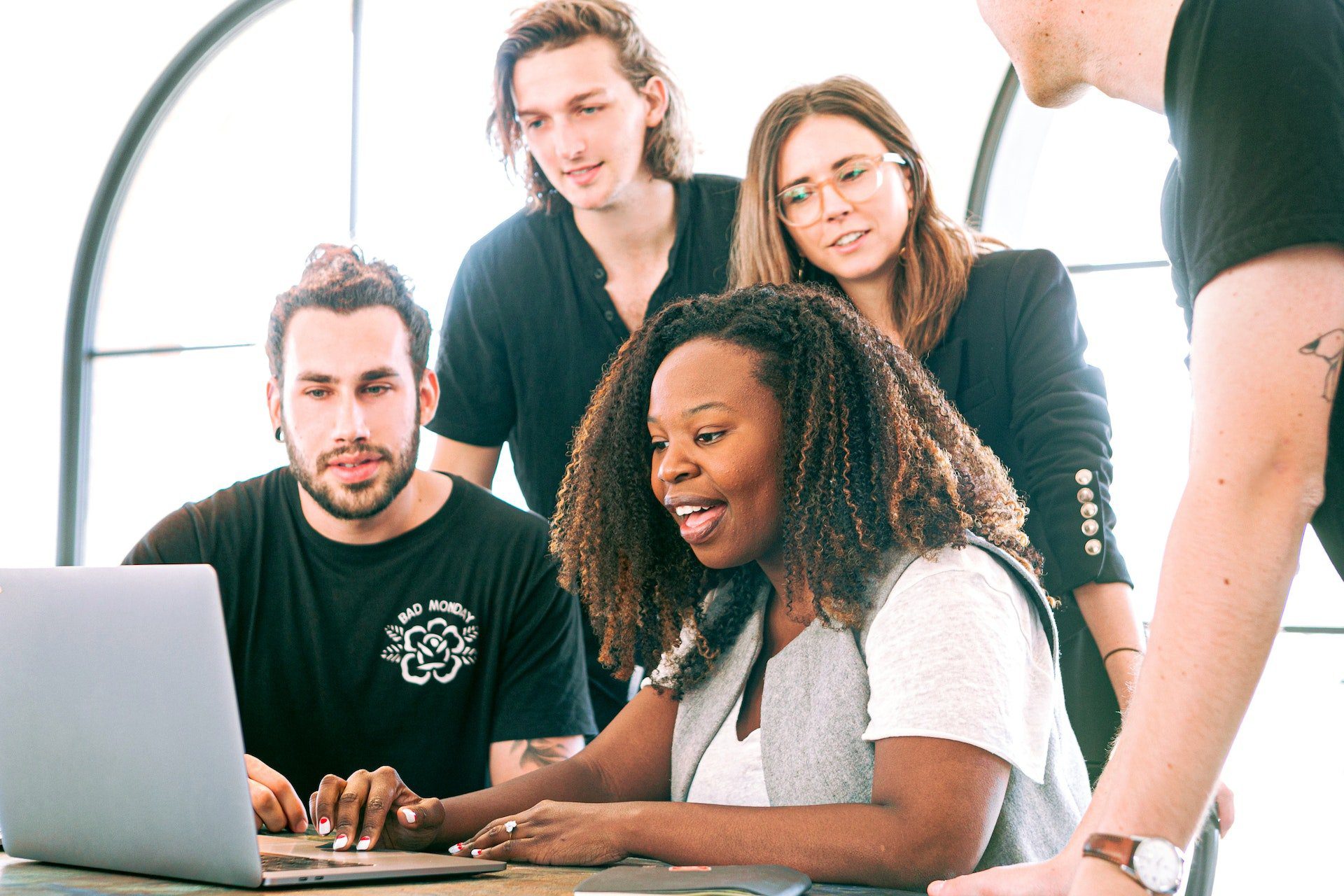 Group of people standing around a laptop watching a presentatition