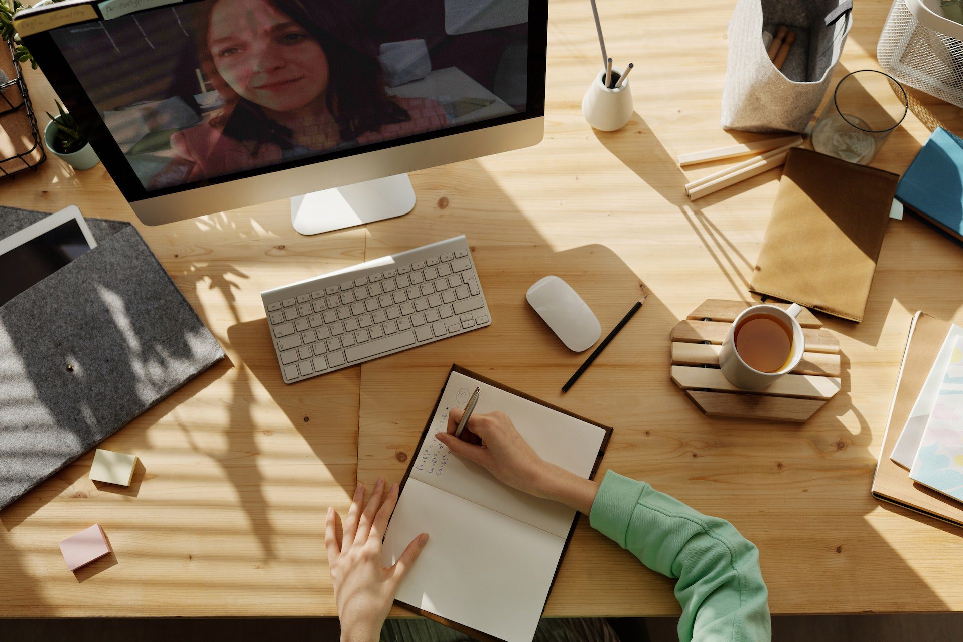 image of someone writing notes by hand while talking to someone on video conferencing on an imac
