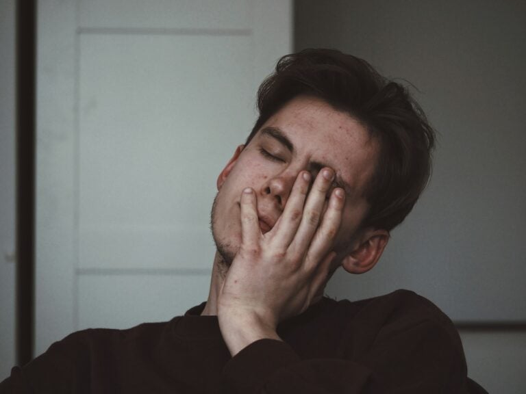 man holding his face illustrating customer pain points