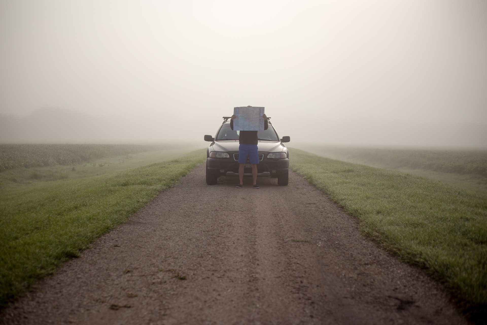 imagen de una persona delante de un coche en una carretera con niebla con un mapa en alto