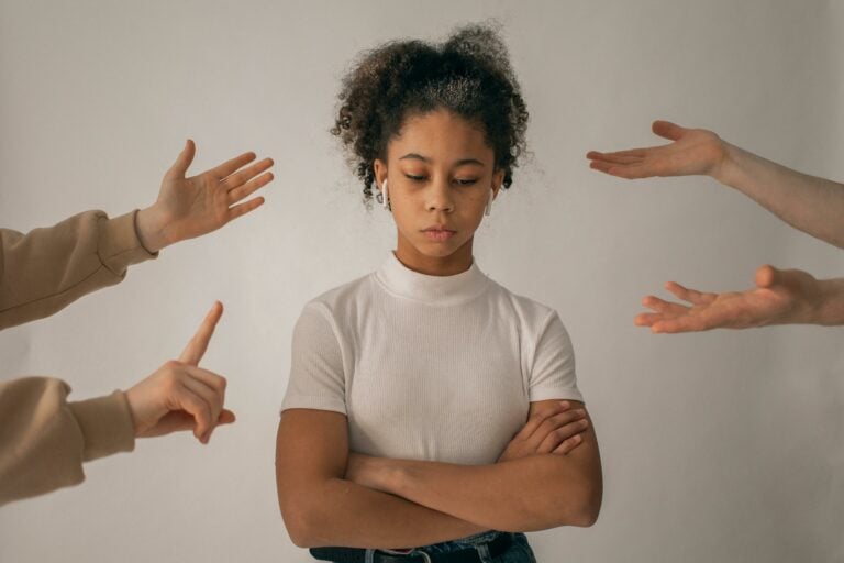 image of a woman with her arms crossed looking negative with hands pointsing at her and telling her what to do to demonstration sales management strategies
