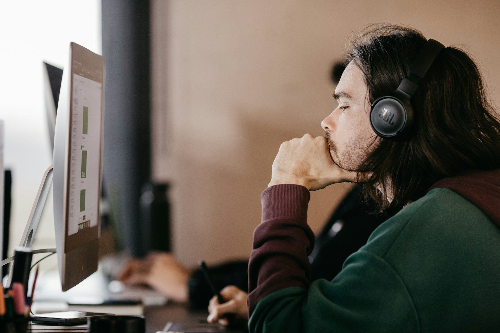 man with headphones on looking at a screen like a person would with an ai meeting note taker